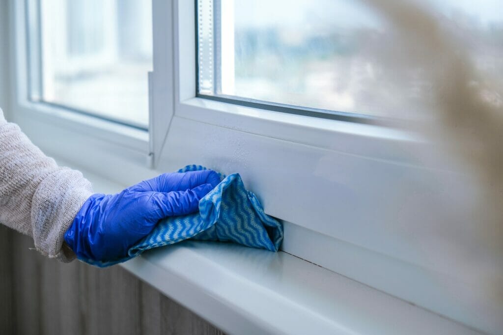 Cleaning the windowsill wiping dust by blue microfiber cloth for cleaning on the glass window rail B